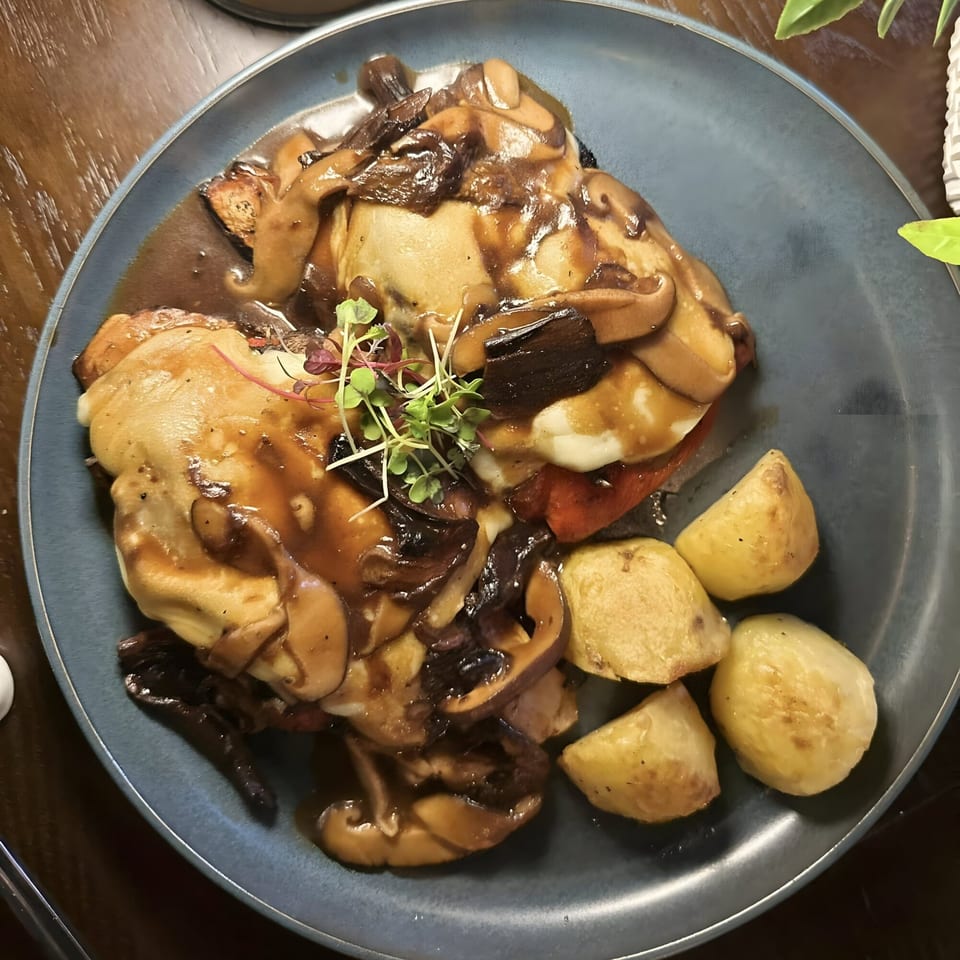 Savory dish with chicken, mushrooms, and gravy, served with roasted potatoes on a blue plate.