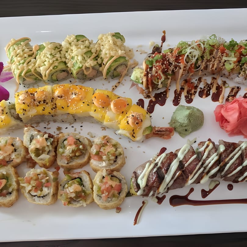 A large platter of various Rio of Japan sushi rolls, including fried, avocado-topped, and seared beef.