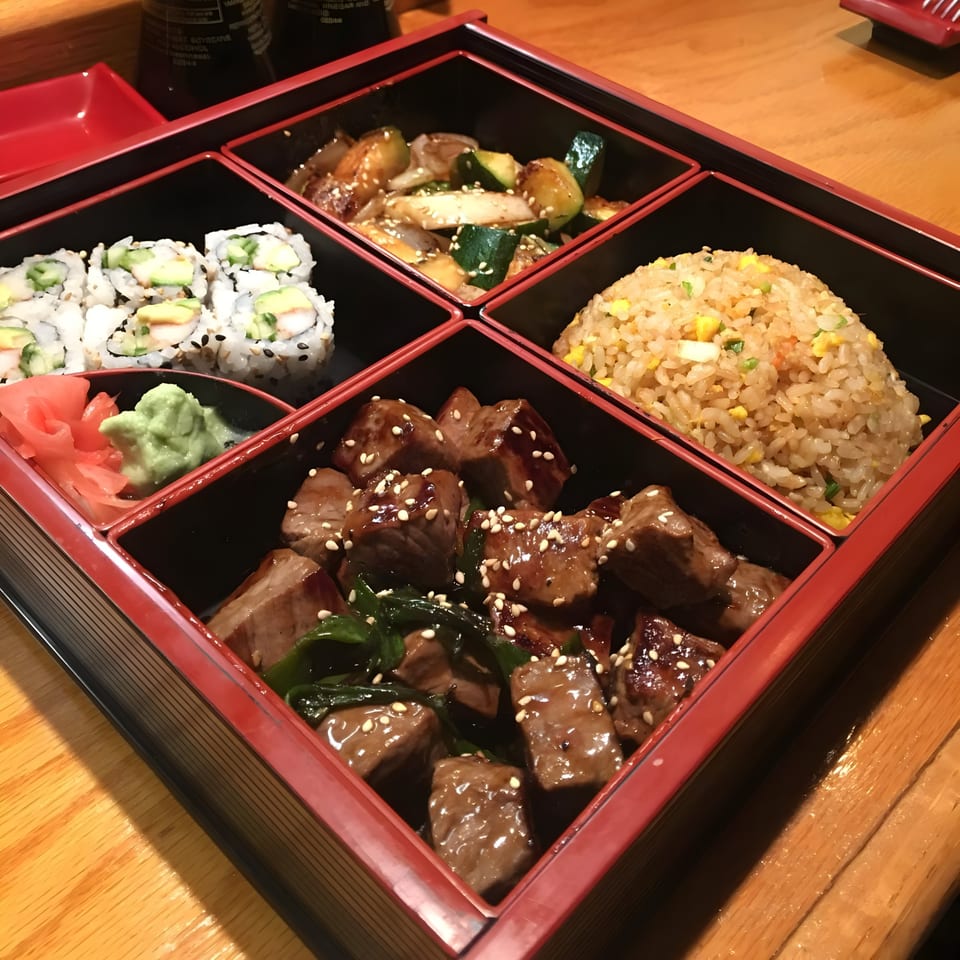 A Rio of Japan bento box with sushi, beef, fried rice, and stir-fried vegetables.
