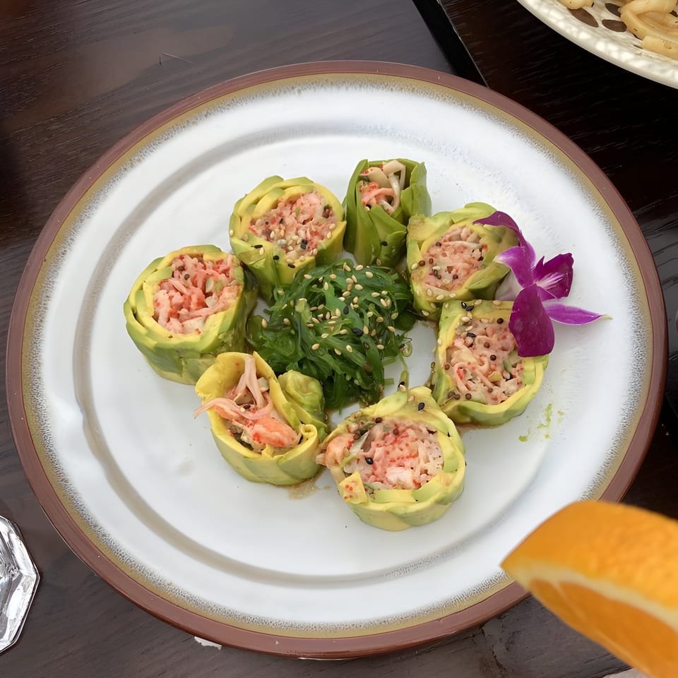 Rio of Japan's avocado-wrapped sushi rolls with crab, seaweed salad, and a purple orchid.