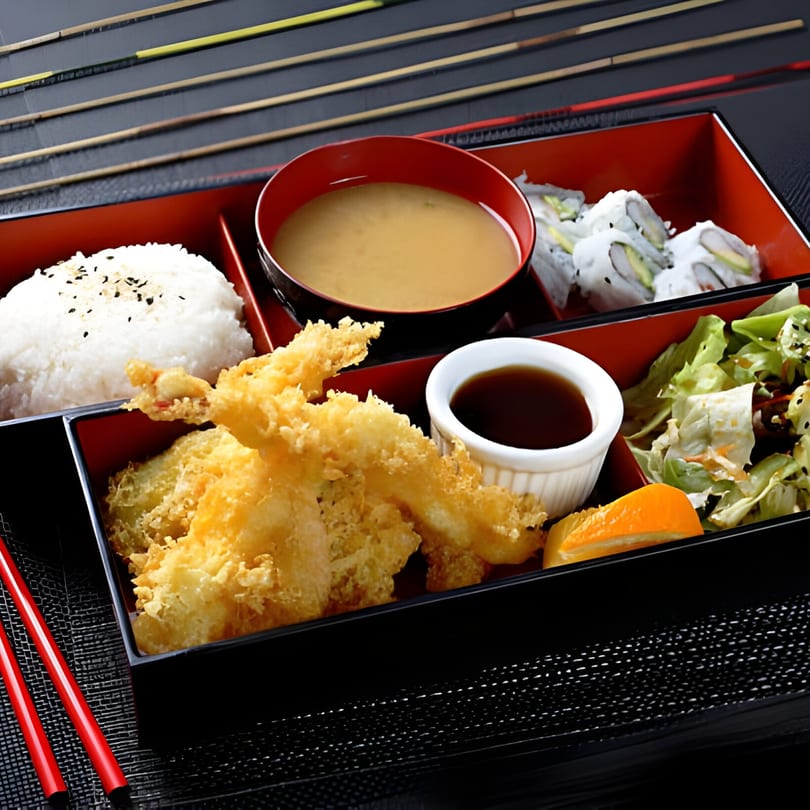 A Rio of Japan bento box with tempura, rice, miso soup, sushi, and salad.