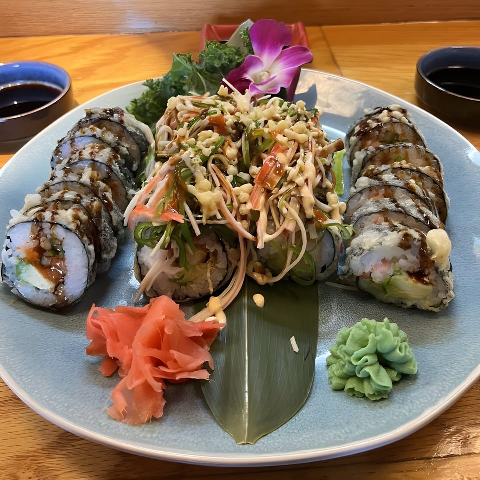 A plate of Rio of Japan sushi rolls, including tempura-fried and topped with crab salad, ginger, and wasabi.